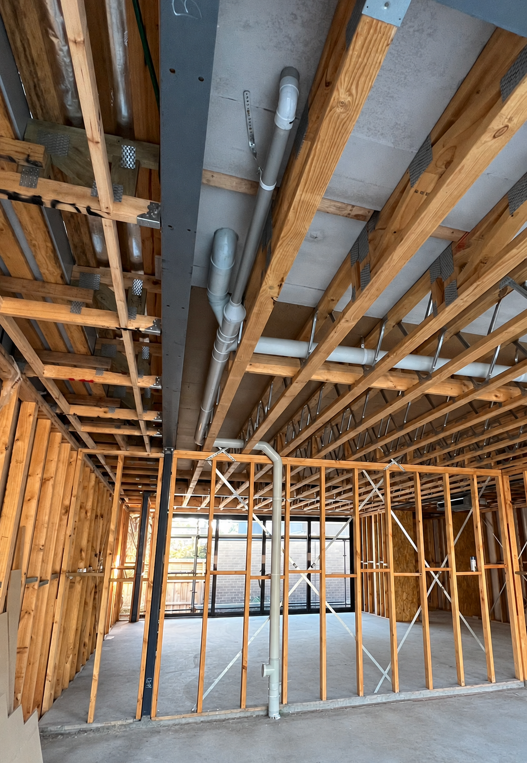 Overhead waste pipework and a vertical stack within timber framing.